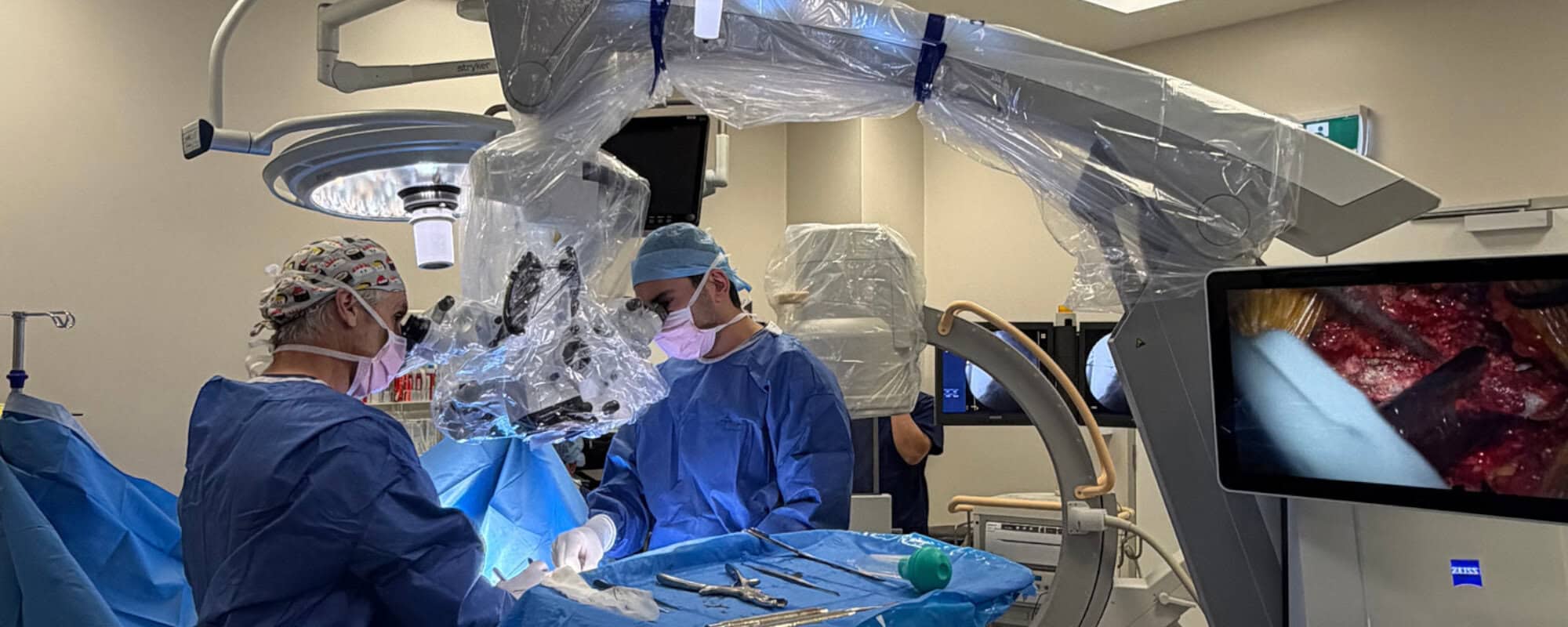 Spinal decompression surgery with the surgical team using a microscope and navigation screen